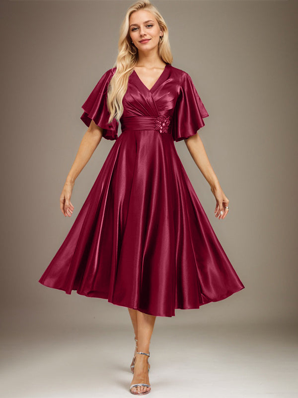 Vestido de novia de satén elástico, corte en A, escote en V, largo hasta la rodilla, con cuentas y pliegues. 