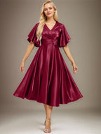 Vestido de novia de satén elástico, corte en A, escote en V, largo hasta la rodilla, con cuentas y pliegues. 