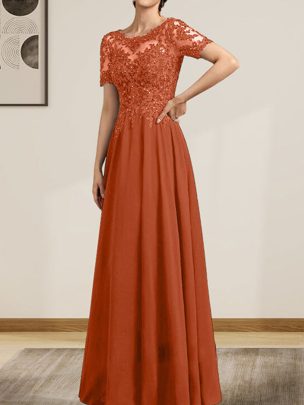 Robe de mariée longue en mousseline de soie et dentelle, coupe trapèze, décolleté illusion, ornée de sequins et de perles.