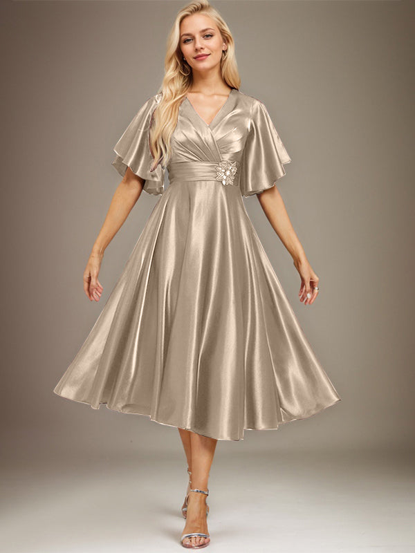 Vestido de novia de satén elástico, corte en A, escote en V, largo hasta la rodilla, con cuentas y pliegues. 