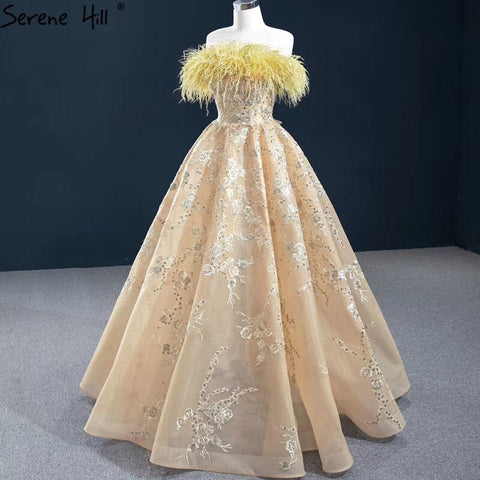 Vestido de noche sexy sin tirantes corte A color champán, con hombros descubiertos, plumas y brillo, modelo HM67164 