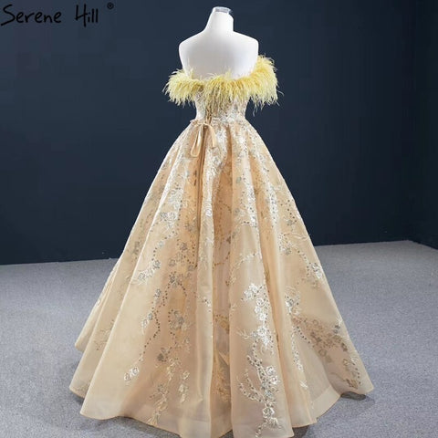 Vestido de noche sexy sin tirantes corte A color champán, con hombros descubiertos, plumas y brillo, modelo HM67164 