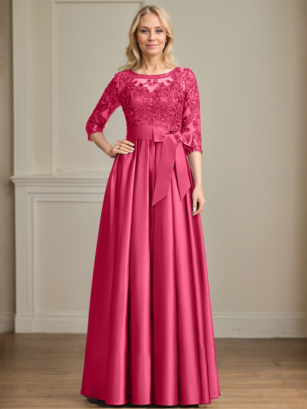 Robe de mariée longue en satin et dentelle, coupe trapèze, décolleté illusion, ornée d'un nœud à sequins. 