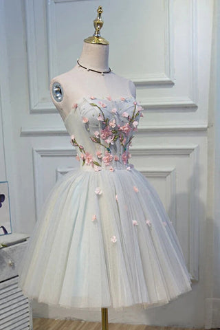 Robe de bal courte en tulle gris mignon, coupe trapèze, décolleté cœur, ornée de fleurs.