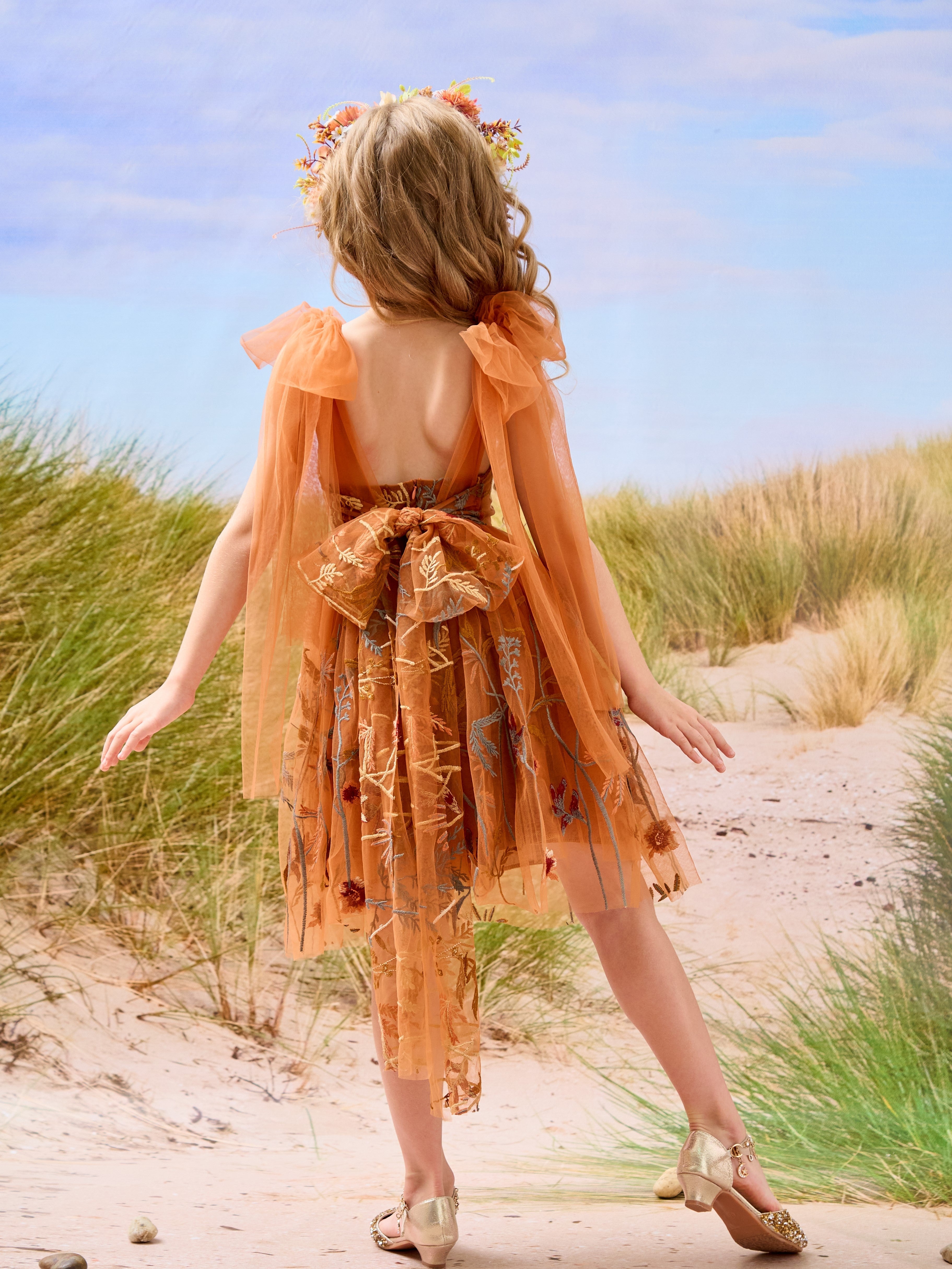Vestido de niña pequeña hasta la rodilla, de encaje y tul color naranja quemado con bordados. 