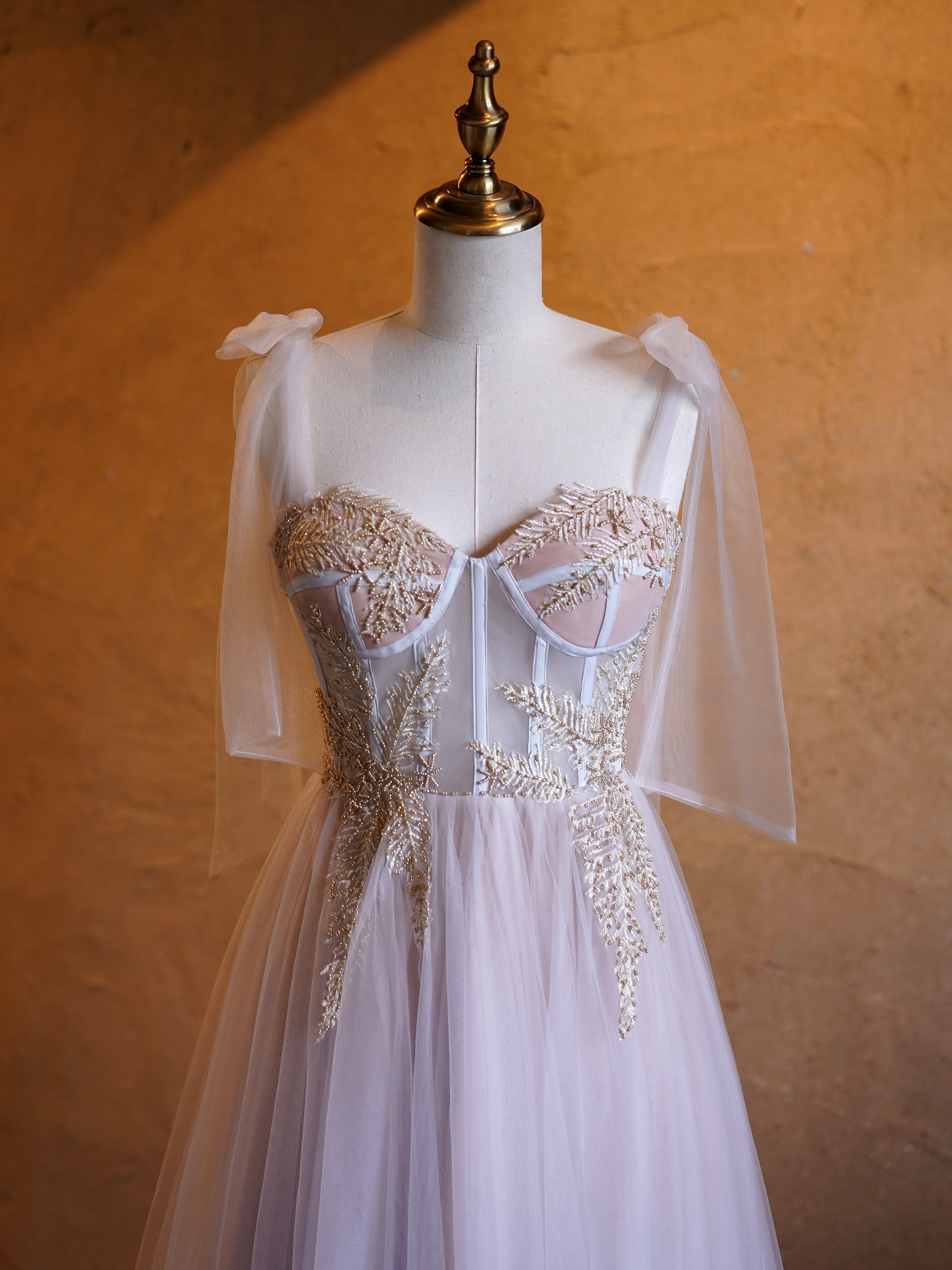 Vestido largo de fiesta de corte A con corsé, apliques de tul, tirantes con lazo y cola de barrido.