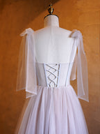 Vestido largo de fiesta de corte A con corsé, apliques de tul, tirantes con lazo y cola de barrido.