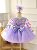 Vestido de bebé niña color lila con lentejuelas, mangas largas con volantes y largo hasta la rodilla 