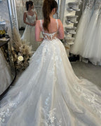 Robe de mariée blanche de créateur, coupe trapèze, bretelles spaghetti, sans manches, en tulle et dentelle.