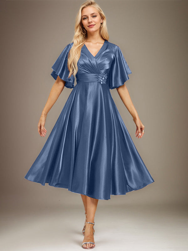 Vestido de novia de satén elástico, corte en A, escote en V, largo hasta la rodilla, con cuentas y pliegues. 