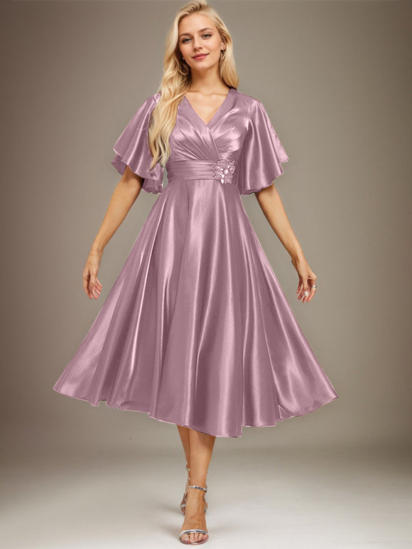 Vestido de novia de satén elástico, corte en A, escote en V, largo hasta la rodilla, con cuentas y pliegues. 