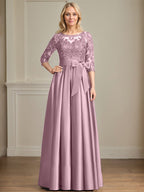 Robe de mariée longue en satin et dentelle, coupe trapèze, décolleté illusion, ornée d'un nœud à sequins. 
