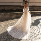 Elegante vestido de novia de corte A, corte sirena, manga larga, hombros descubiertos, escote corazón, tul, apliques de lentejuelas y color beige. 