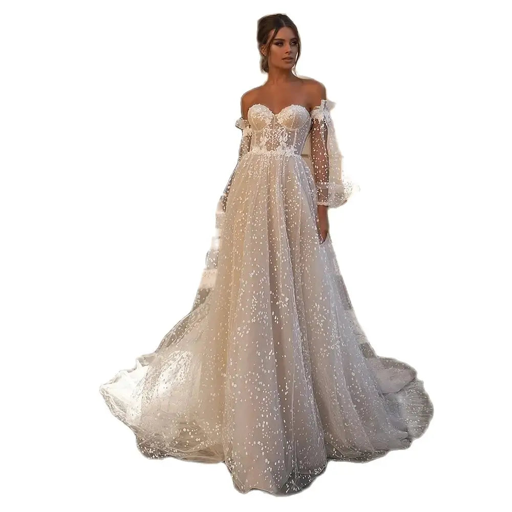 Elegante vestido de novia de corte A, corte sirena, manga larga, hombros descubiertos, escote corazón, tul, apliques de lentejuelas y color beige. 
