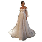 Elegante vestido de novia de corte A, corte sirena, manga larga, hombros descubiertos, escote corazón, tul, apliques de lentejuelas y color beige. 