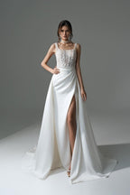 Robe de mariée blanche élégante, longue, trapèze, ornée de perles et de dentelle, sans manches et fendue.