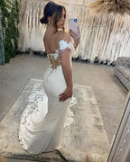 Elegante vestido de novia largo blanco de corte sirena con hombros descubiertos, apliques y cola