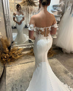 Elegante vestido de novia largo blanco de corte sirena con hombros descubiertos, apliques y cola