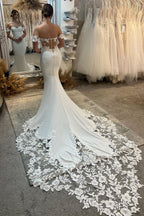 Elegante vestido de novia largo blanco de corte sirena con hombros descubiertos, apliques y cola