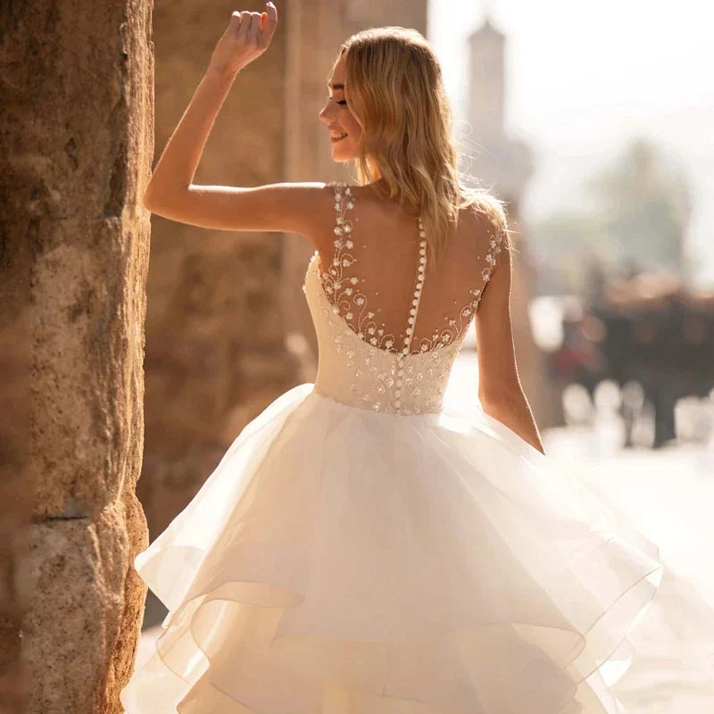 Robes de mariée élégantes à décolleté cœur 2024, ornées d'appliqués floraux, sans manches, dos illusion, à volants et traîne courte.