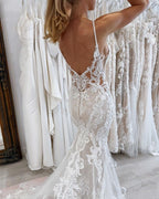 Magnifique robe de mariée blanche sirène en tulle et dentelle, sans manches, à fines bretelles spaghetti et traîne ornée d'appliqués.