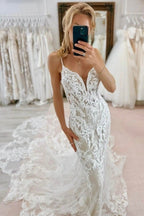 Magnifique robe de mariée blanche sirène en tulle et dentelle, sans manches, à fines bretelles spaghetti et traîne ornée d'appliqués.
