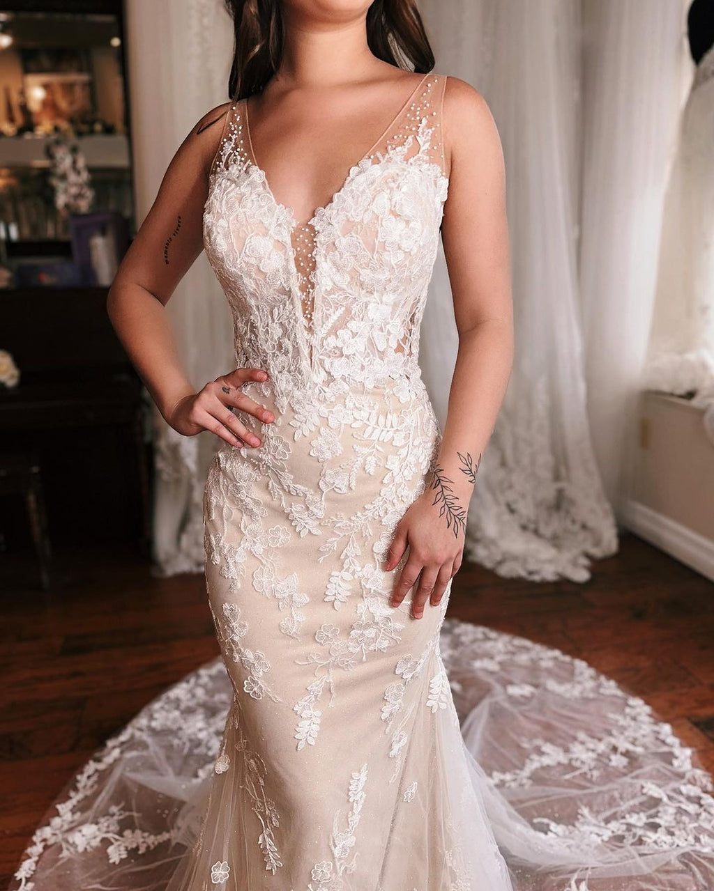 Robe de mariée sirène longue et glamour, sans manches, dos nu et décolleté en V, ornée de dentelle.