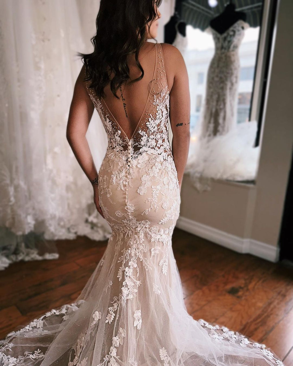 Robe de mariée sirène longue et glamour, sans manches, dos nu et décolleté en V, ornée de dentelle.