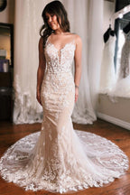 Robe de mariée sirène longue et glamour, sans manches, dos nu et décolleté en V, ornée de dentelle.