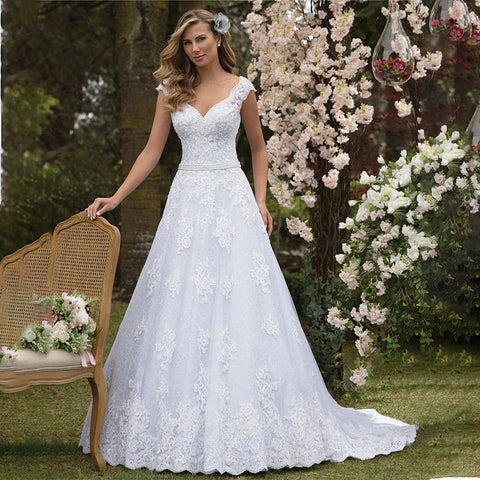Vestidos de novia de corte A con elegante escote en V de tul y encaje, con apliques y pedrería, fajín y corte nupcial. 
