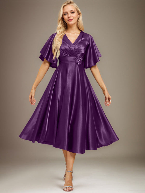 Vestido de novia de satén elástico, corte en A, escote en V, largo hasta la rodilla, con cuentas y pliegues. 