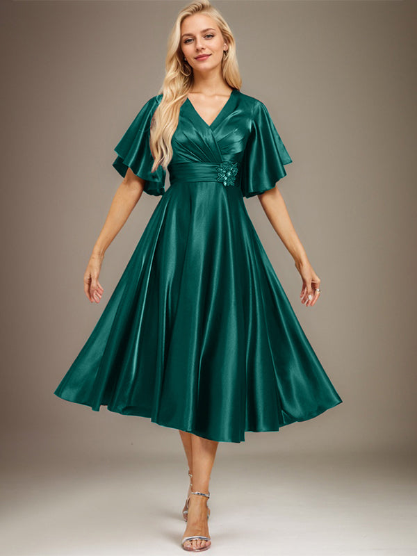 Vestido de novia de satén elástico, corte en A, escote en V, largo hasta la rodilla, con cuentas y pliegues. 