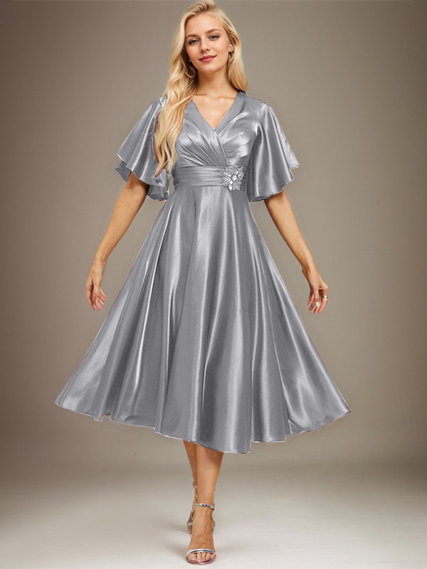 Vestido de novia de satén elástico, corte en A, escote en V, largo hasta la rodilla, con cuentas y pliegues. 
