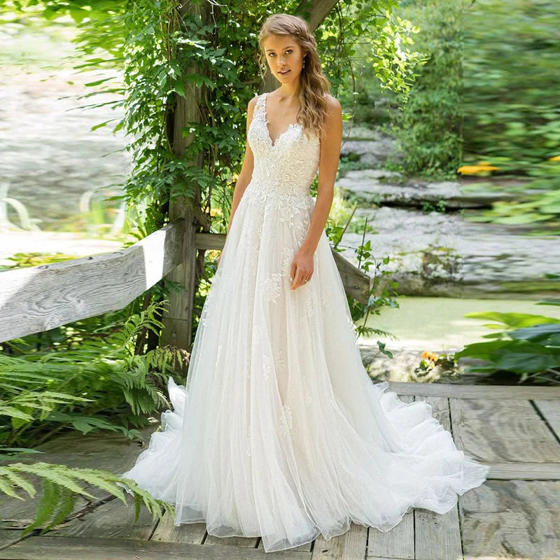 Robe de mariée haute couture élégante en tulle blanc dos nu à fines bretelles, traîne, décolleté en V et broderies, coupe trapèze. 