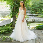 Robe de mariée haute couture élégante en tulle blanc dos nu à fines bretelles, traîne, décolleté en V et broderies, coupe trapèze. 