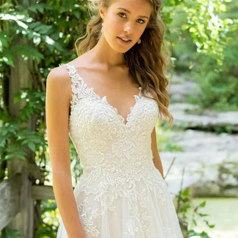 Robe de mariée haute couture élégante en tulle blanc dos nu à fines bretelles, traîne, décolleté en V et broderies, coupe trapèze. 