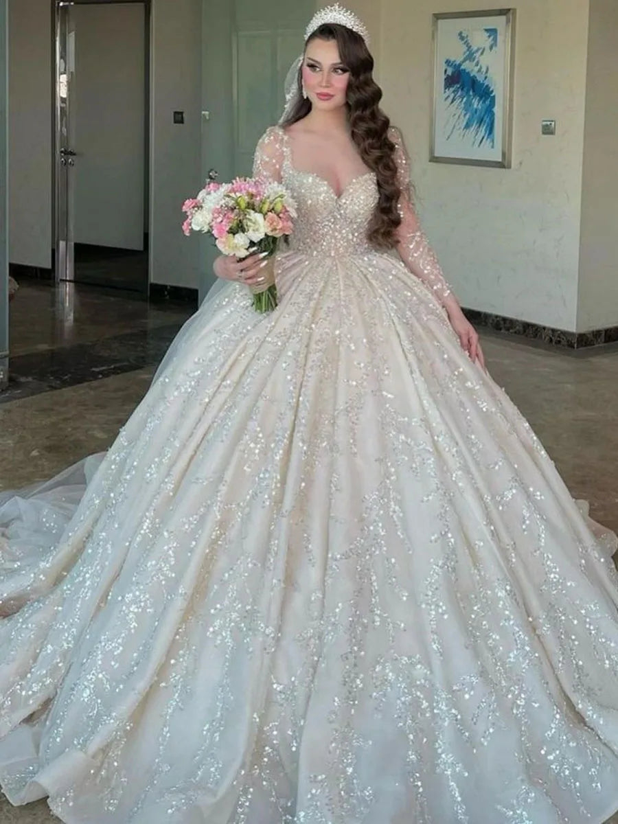 Vestido de novia blanco romántico de alta costura con mangas largas, encaje, pedrería, lentejuelas, escote en V y largo hasta el suelo. 