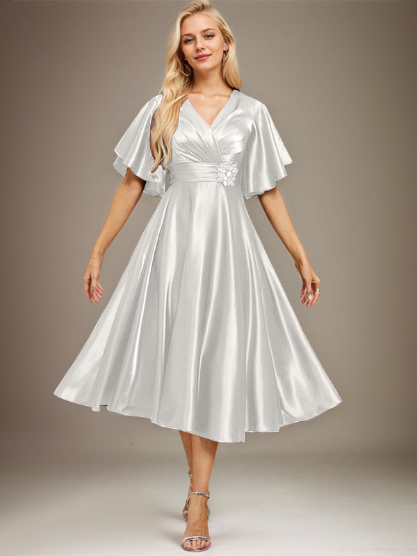 Vestido de novia de satén elástico, corte en A, escote en V, largo hasta la rodilla, con cuentas y pliegues. 