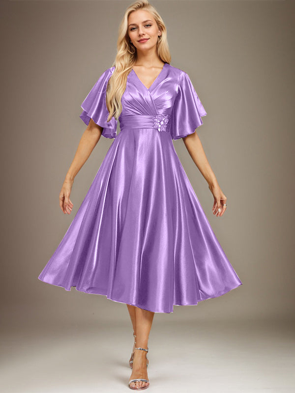 Vestido de novia de satén elástico, corte en A, escote en V, largo hasta la rodilla, con cuentas y pliegues. 