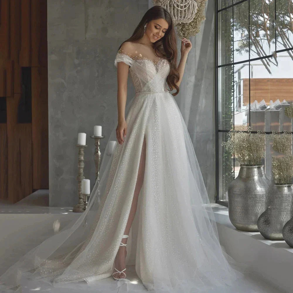 Robe de mariée sirène luxueuse et élégante en dentelle et perles, épaules dénudées, volants vaporeux, collection 2023, ornée d'appliqués féeriques.