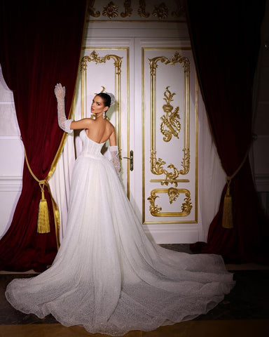 Lujoso vestido de novia largo color marfil, corte sirena, sin mangas, con escote en V, lentejuelas y pedrería, con cola desmontable.