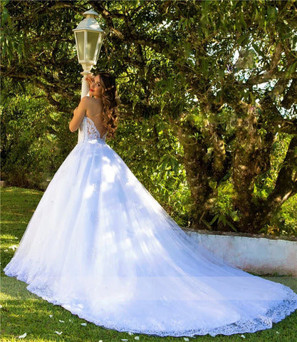 Robe de mariée blanche de luxe, dos nu, décolleté en cœur, ornée d'appliqués, en tulle de perles et de cristaux, style saoudien. 