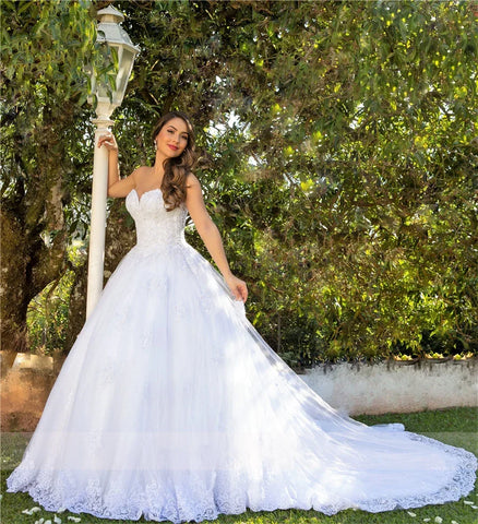 Robe de mariée blanche de luxe, dos nu, décolleté en cœur, ornée d'appliqués, en tulle de perles et de cristaux, style saoudien. 