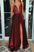 Robe de bal bordeaux fendue, ornée de perles, avec poches et col en V, coupe trapèze.