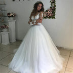 Robe de mariée MYYBLE Illusion à manches longues et décolleté arrondi, ornée d'appliqués de dentelle et d'un dos transparent, en tulle blanc/ivoire.