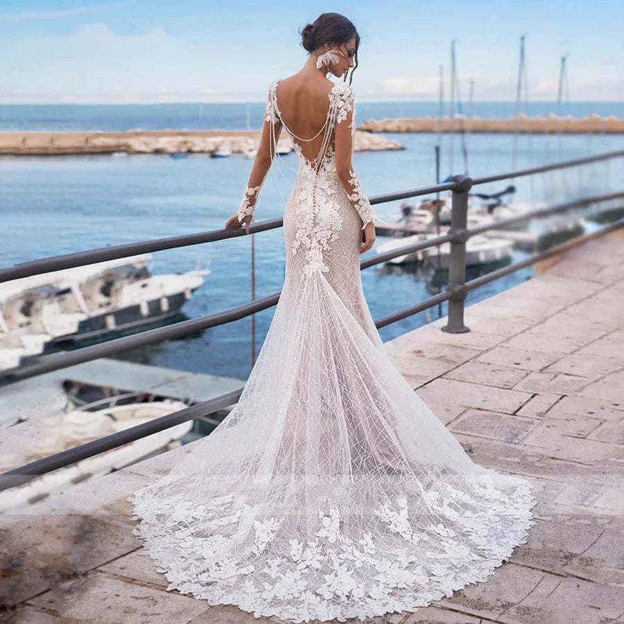 Robe de mariée sirène sexy dos nu à manches longues, broderies et applications de dentelle, idéale pour un mariage sur la plage ou une fête.