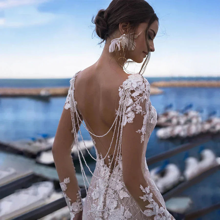 Robe de mariée sirène sexy dos nu à manches longues, broderies et applications de dentelle, idéale pour un mariage sur la plage ou une fête.