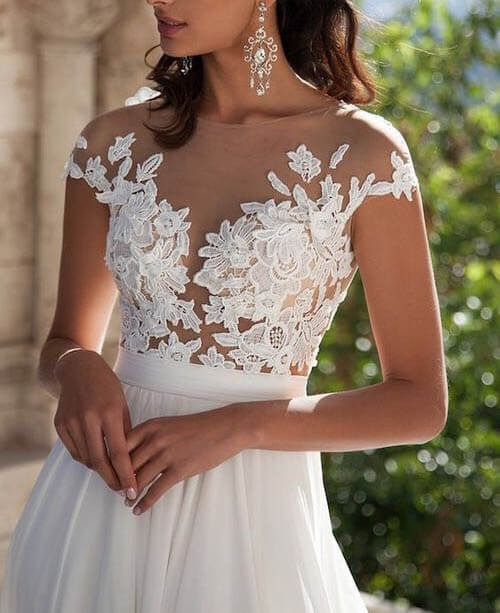 Vestido de novia blanco de encaje con corte en A, abertura frontal y apliques.