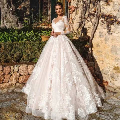 Vestido de novia de corte princesa, elegante, de manga larga, con espalda ilusión y escote redondo.