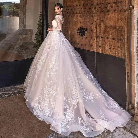 Vestido de novia de corte princesa, elegante, de manga larga, con espalda ilusión y escote redondo.